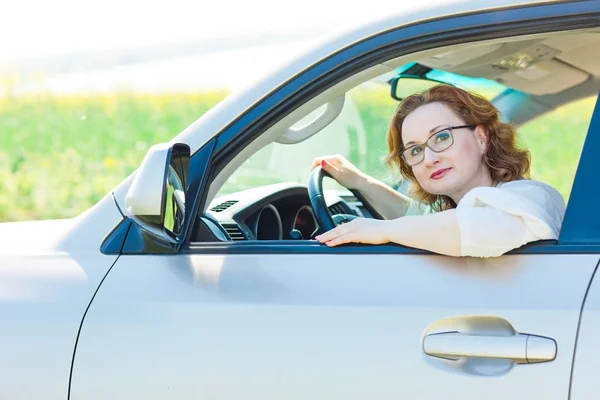 Aantrekkelijke vrouw poseren in auto op bestuurdersstoel. — Stockfoto