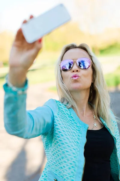 Donna bionda con occhiali da sole fare selfie . — Foto Stock