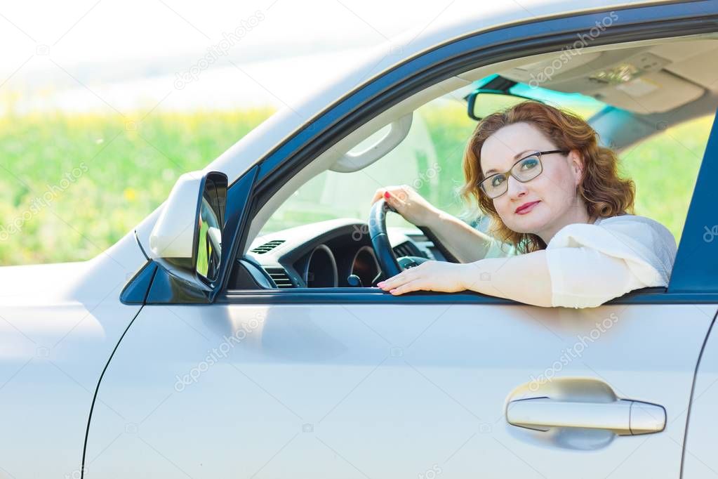 Attractive woman posing in car on drivers seat.