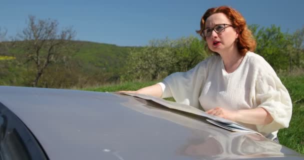 Frau Sucht Mit Papierkarte Auf Motorhaube Die Richtige Richtung Orientierungslosigkeit — Stockvideo