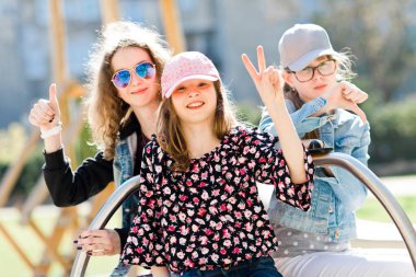 Oyun alanında üç genç kız küçük atlıkarınca üzerinde oturan - zafer, yukarı thump ve aşağı thump