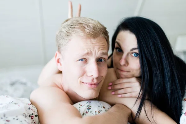 Красивий чоловік і гарна жінка позує в ліжку - роблячи вуха кролика — стокове фото