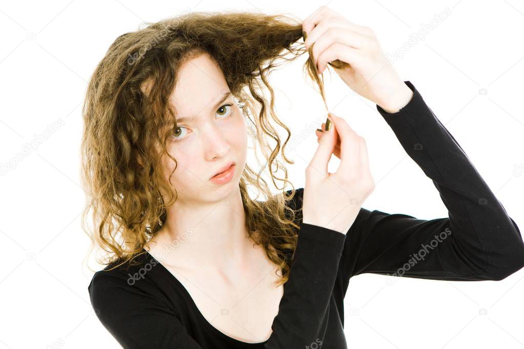 Teenaged blond girl with curly hair having tangled hair ends problem.