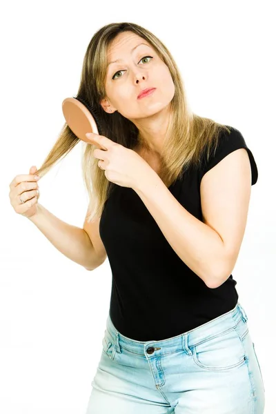 Ξανθιά γυναίκα βουρτσίζει ομαλά μακριά ίσια μαλλιά με βούρτσα μαλλιών. — Φωτογραφία Αρχείου
