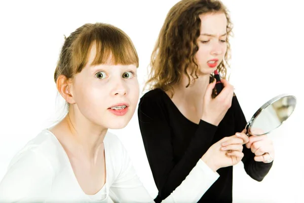 Две девочки-подростки, одна с двумя девочками-подростками, одна с брекетами, в половом созревании торгуются, чтобы получить зеркало, чтобы сделать макияж торг, чтобы получить зеркало, чтобы сделать макияж - сестра соперничество . — стоковое фото