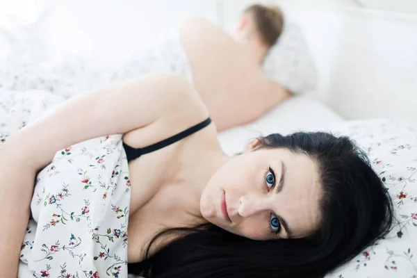 Verzweifelte junge Frau mit offenen Augen im Bett. — Stockfoto