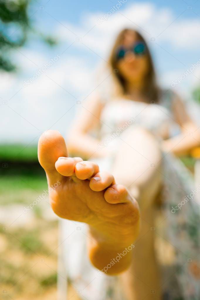 A woman sitting on camp chair and sunbathing - toes