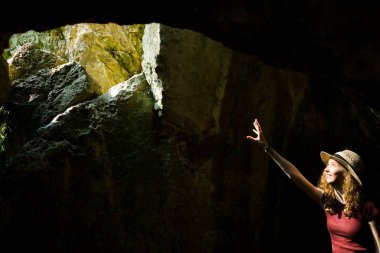 Genç kaşif şapkalı bir kız kadim mağarayı işaret ediyor.