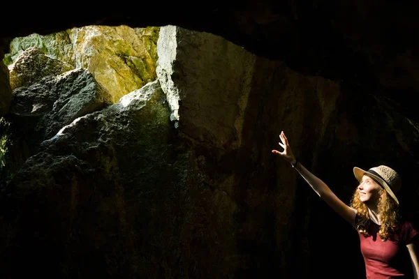 Genç kaşif şapkalı bir kız kadim mağarayı işaret ediyor.