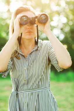 Bir gözlemci dışarıda siyah dürbün kullanıyor..