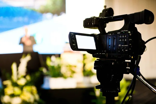 Filming conference with video camera on tripod.