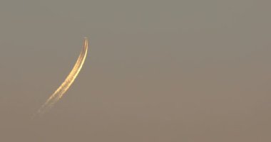 Gün batımında gökyüzünde kontrastlı yüksek uçaklar. Uçak uzak mesafeden yaklaşıyor.