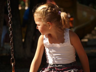 bir beyaz beş yaşında bir kız T-shirt bir tahterevalli bir şehir parkta oturuyor