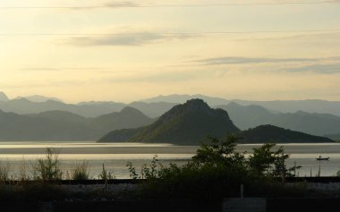 İşkodra Gölü, dağlar ve gün batımında yalnız bir tekne görünümü