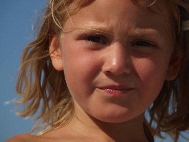 mavi bir gökyüzü yaz gününde küçük bir hoşnutsuz kız closeup portre