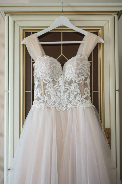 wedding dress on hanger on a wall. Beautiful gown