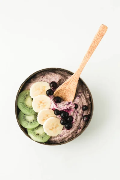 Healthy smoothie with fruits, plate made from coconut shell and wood spoon — Stock Photo, Image