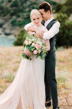 Çarpıcı gelin ve damat kucaklamak birbirlerine ihale ayakta altın tepe üzerinde