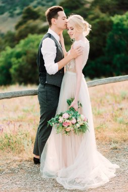 Çarpıcı gelin ve damat kucaklamak birbirlerine ihale ayakta altın tepe üzerinde