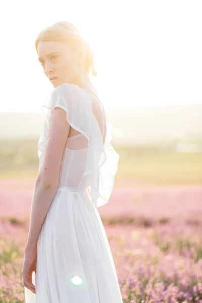 Verkümmerndes Porträt eines Mädchens im hellen Kleid im Lavendelfeld bei Sonnenuntergang — Stockfoto