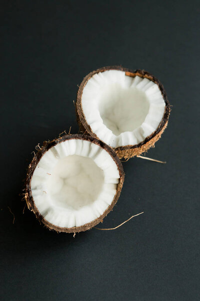 Broken ripe coconut on black background. White flesh