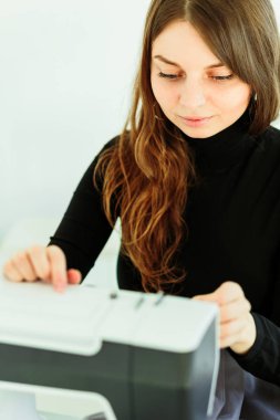 Genç terzi kadın dikiş makinesine elbise dikiyor..