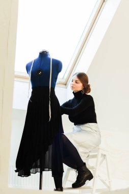 Genç bir terzi kadın manken üzerinde giysi setleri.