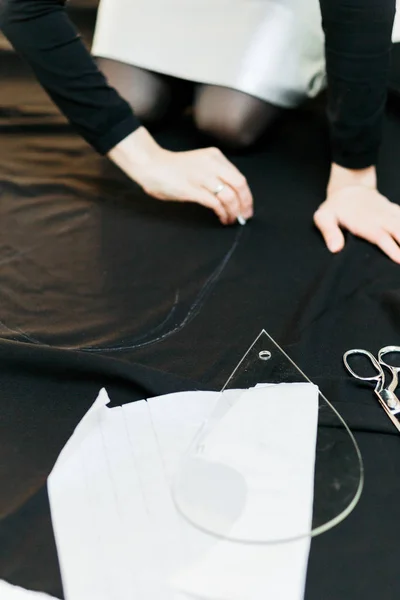 Hermosa costurera, corte de tela negra en el piso del estudio —  Fotos de Stock