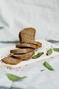Gri bir bez üzerinde tahta bir tahta üzerinde taze dilimlenmiş ekmek