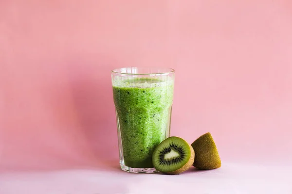 Smoothie vert sain avec kiwi dans une tasse en verre sur un fond rose — Photo