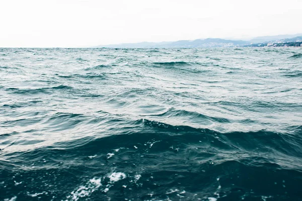 Ondulaciones en el agua de mar azul con espuma blanca, fondo marino natural —  Fotos de Stock