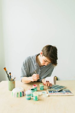 çömlek kadın elinde süs boyamak için bir kupa tutar