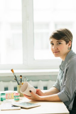 çömlek kadın elinde süs boyamak için bir kupa tutar