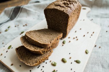 Gri bir bez üzerinde tahta bir tahta üzerinde taze dilimlenmiş ekmek