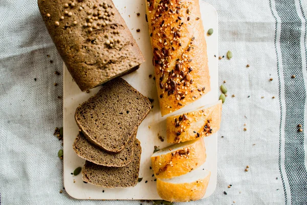 Freshly baked white and grey bread on dark grey fabric with seed — Stock Photo, Image