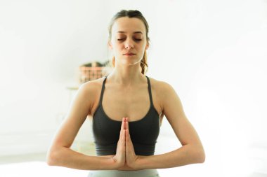 Parlak bir odada yoga yapan çekici, gülümseyen bir kadın.