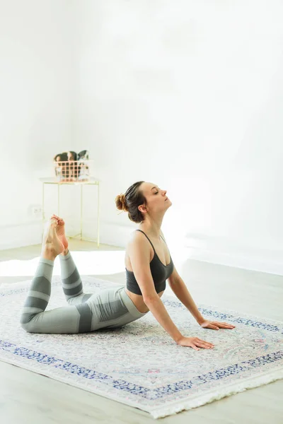 Młoda, atrakcyjna, uśmiechnięta kobieta ćwicząca jogę w jasnym pokoju — Zdjęcie stockowe