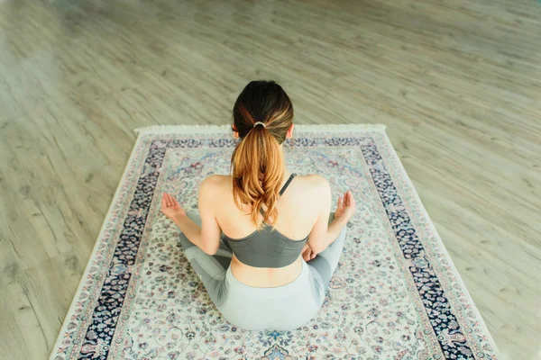 Fiatal vonzó mosolygós nő gyakorló jóga egy világos szobában — Stock Fotó