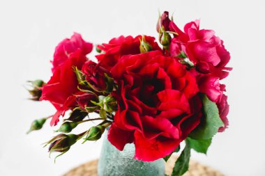 Beyaz arka planda bir hasır peçete üzerinde vazo coloful güller