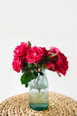 Beyaz arka planda bir hasır peçete üzerinde vazo coloful güller