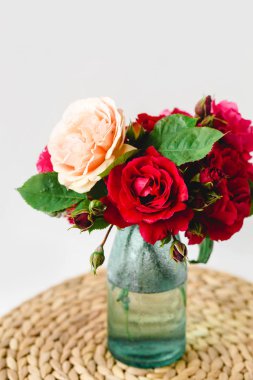 Beyaz arka planda bir hasır peçete üzerinde vazo coloful güller