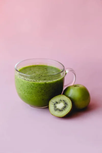 Smoothie vert sain avec kiwi et pomme dans une tasse en verre sur fond rose — Photo