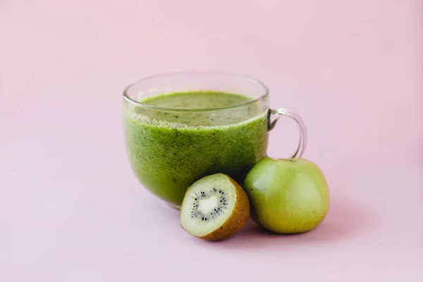 Smoothie vert sain avec kiwi et pomme dans une tasse en verre sur fond rose — Photo