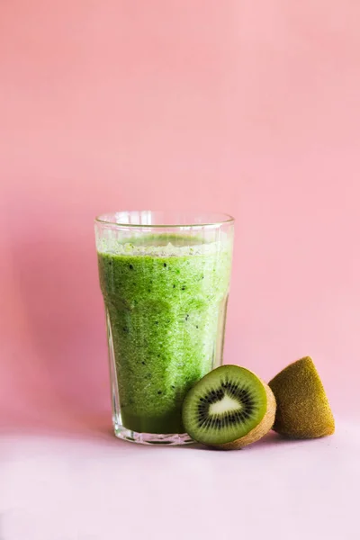 Smoothie vert sain avec kiwi dans une tasse en verre sur un fond rose — Photo