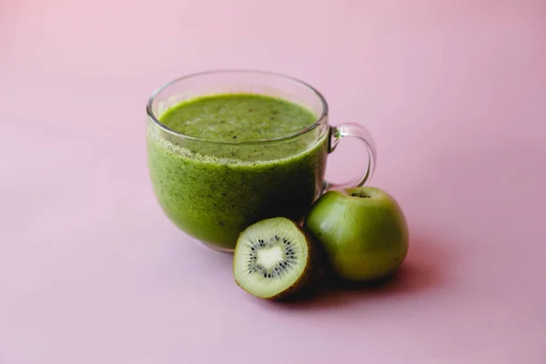 Smoothie vert sain avec kiwi et pomme dans une tasse en verre sur fond rose — Photo