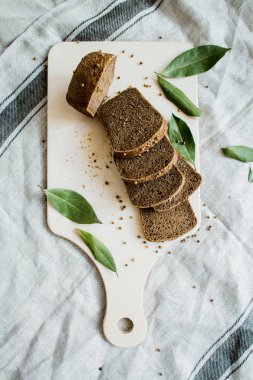 Gri bir bez üzerinde tahta bir tahta üzerinde taze dilimlenmiş ekmek