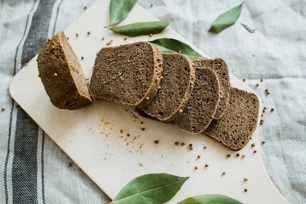 Pão fresco fatiado em uma tábua de madeira em um pano cinza — Fotografia de Stock