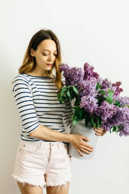 Beyaz bir arka plan üzerinde leylak bir menekşe buketi ile çekici kız
