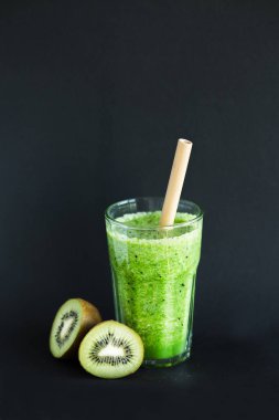 Siyah bir arka planda bir cam fincan kivi ile sağlıklı yeşil smoothie