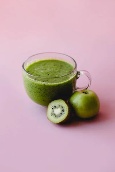 Smoothie vert sain avec kiwi dans une tasse en verre sur un fond rose — Photo